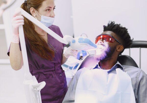 Dentist performing teeth whitening procedure on patient